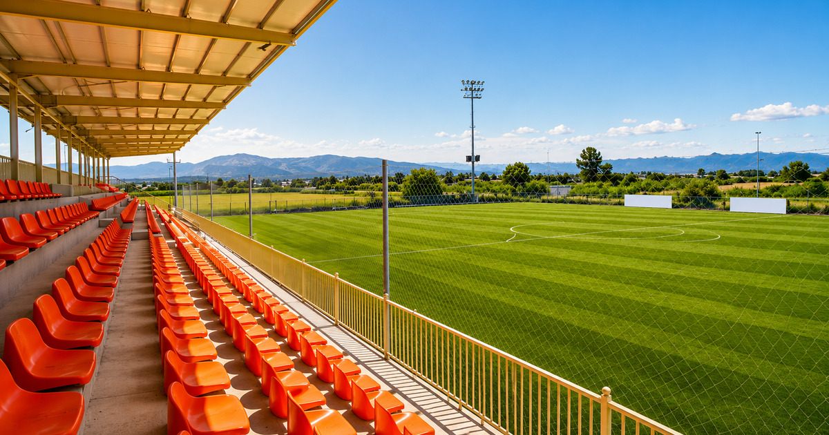 View from covered grandstand across FIFA-standard football pitch with mountains in the background, Antalya