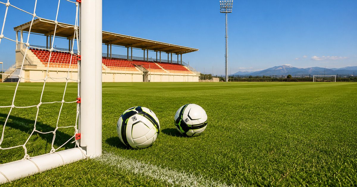 Two footballs by the goalpost on a FIFA-standard pitch with grandstand and mountains behind, Side Turkey