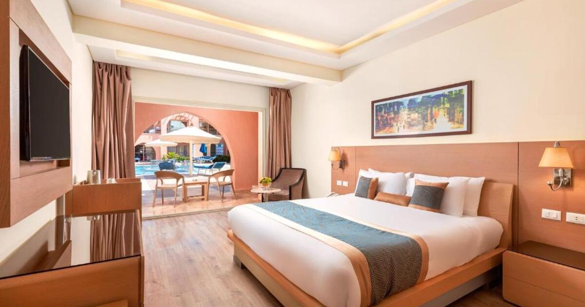 Pool-view room with king bed, warm lighting, flat-screen TV and sliding doors opening directly onto the pool terrace, Hurghada resort