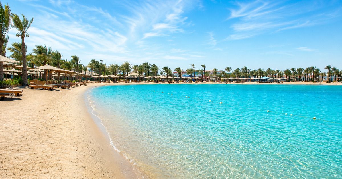 Turquoise lagoon beach with sun loungers and palm trees at a Red Sea resort in Hurghada, Egypt