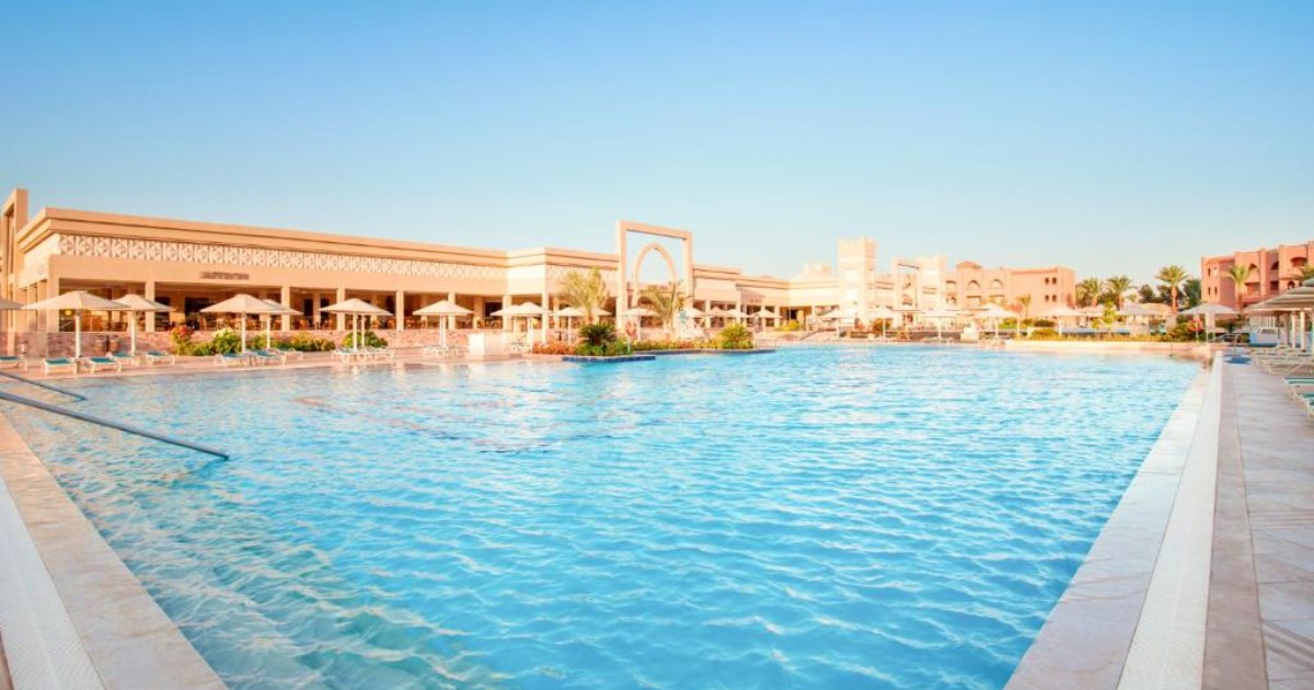 Large outdoor resort swimming pool with sun loungers and all-inclusive hotel buildings in Hurghada
