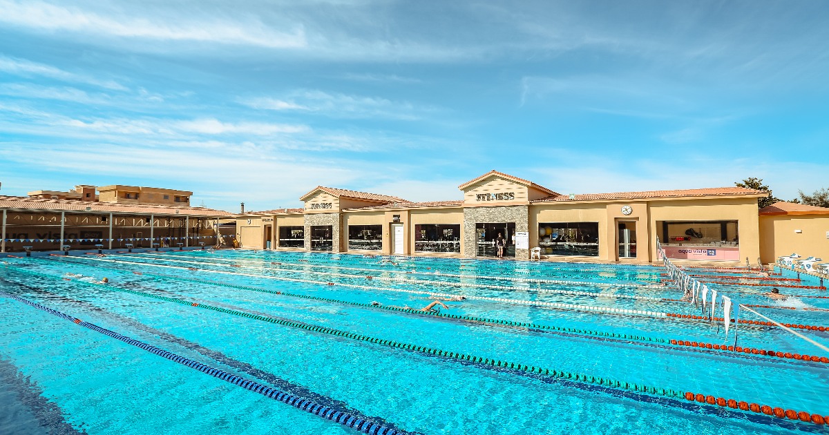 Outdoor 50m Olympic swimming pool with lane ropes beside resort fitness buildings in Hurghada, Egypt