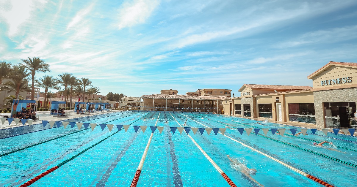 Competitive swimmers training in an outdoor 50m pool with lane ropes and flags at a Hurghada resort