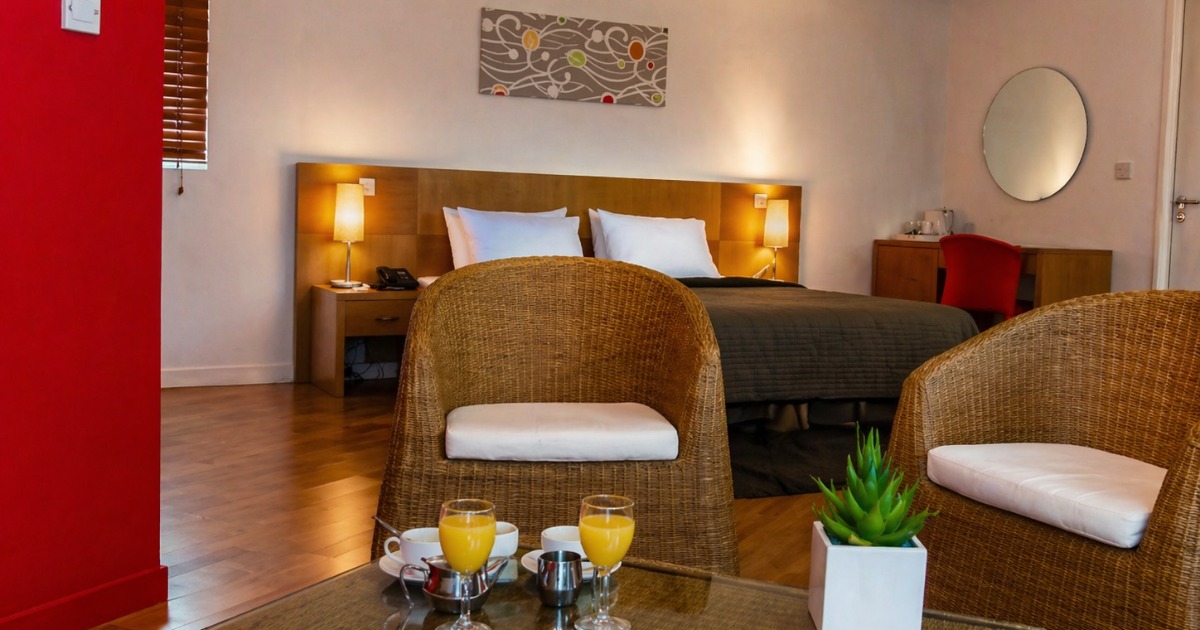 Executive room with bed, wicker armchairs, and a coffee table set with juice and refreshments