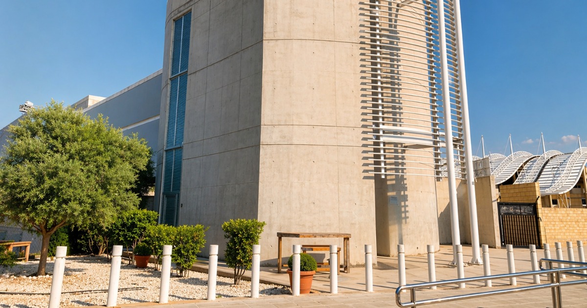 Concrete exterior of the sports residence with the tented stadium roof visible in the background