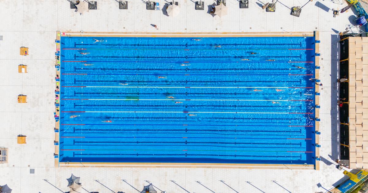 Overhead aerial view of a 10-lane outdoor pool with swimmers training in multiple lanes
