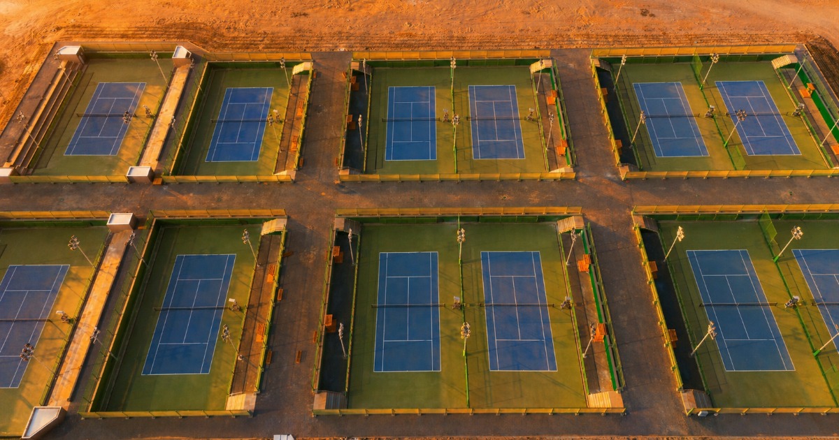Aerial view of six ITF-standard tennis courts at Soma Bay, Egypt, arranged in two rows and bathed in warm evening light
