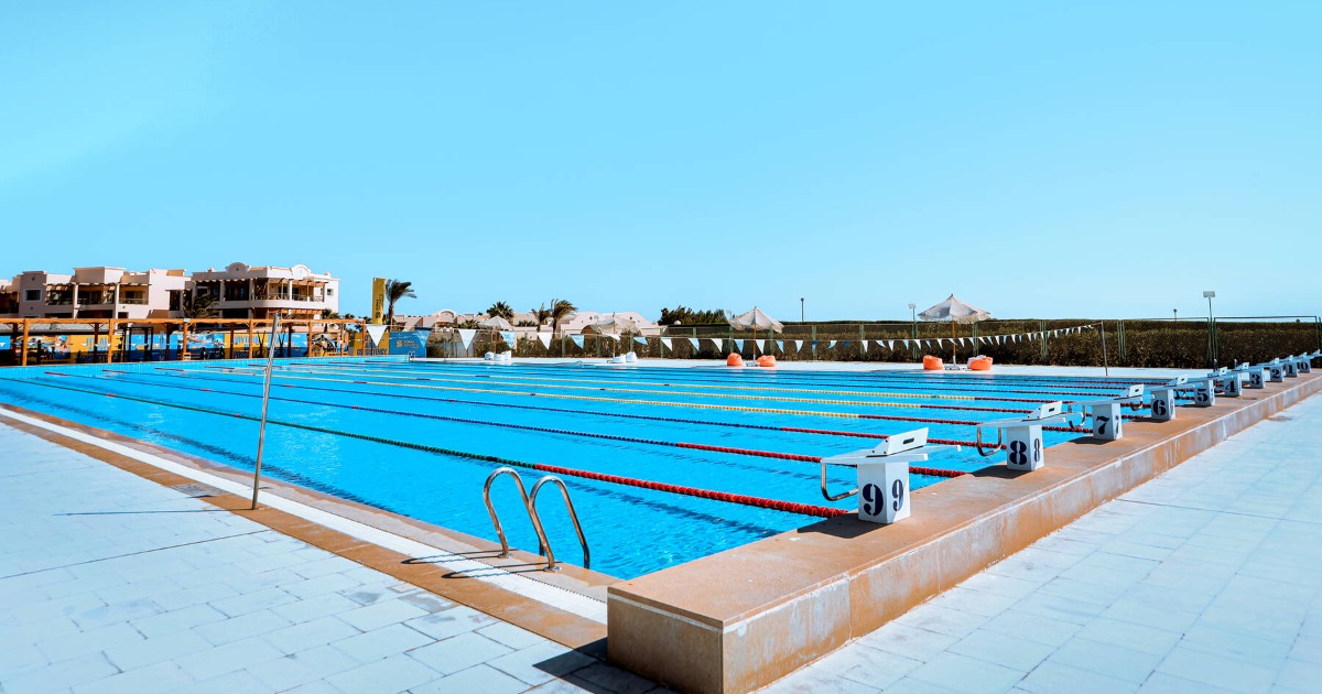 Soma Bay 50m pool — starting block view looking down lanes 5 and 6 with resort buildings behind